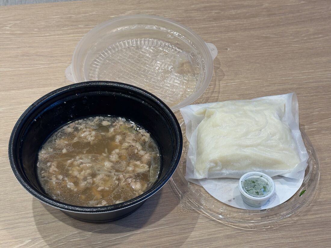 プラスチック製の容器には、出汁（肉入り）と麺、ネギが入っている