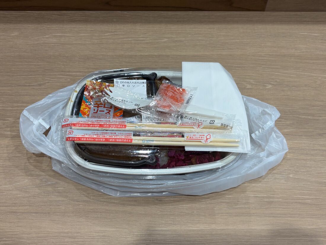 容器の上にスプーンと箸、ナプキン、紅しょうが、辛口ソースが付属されている